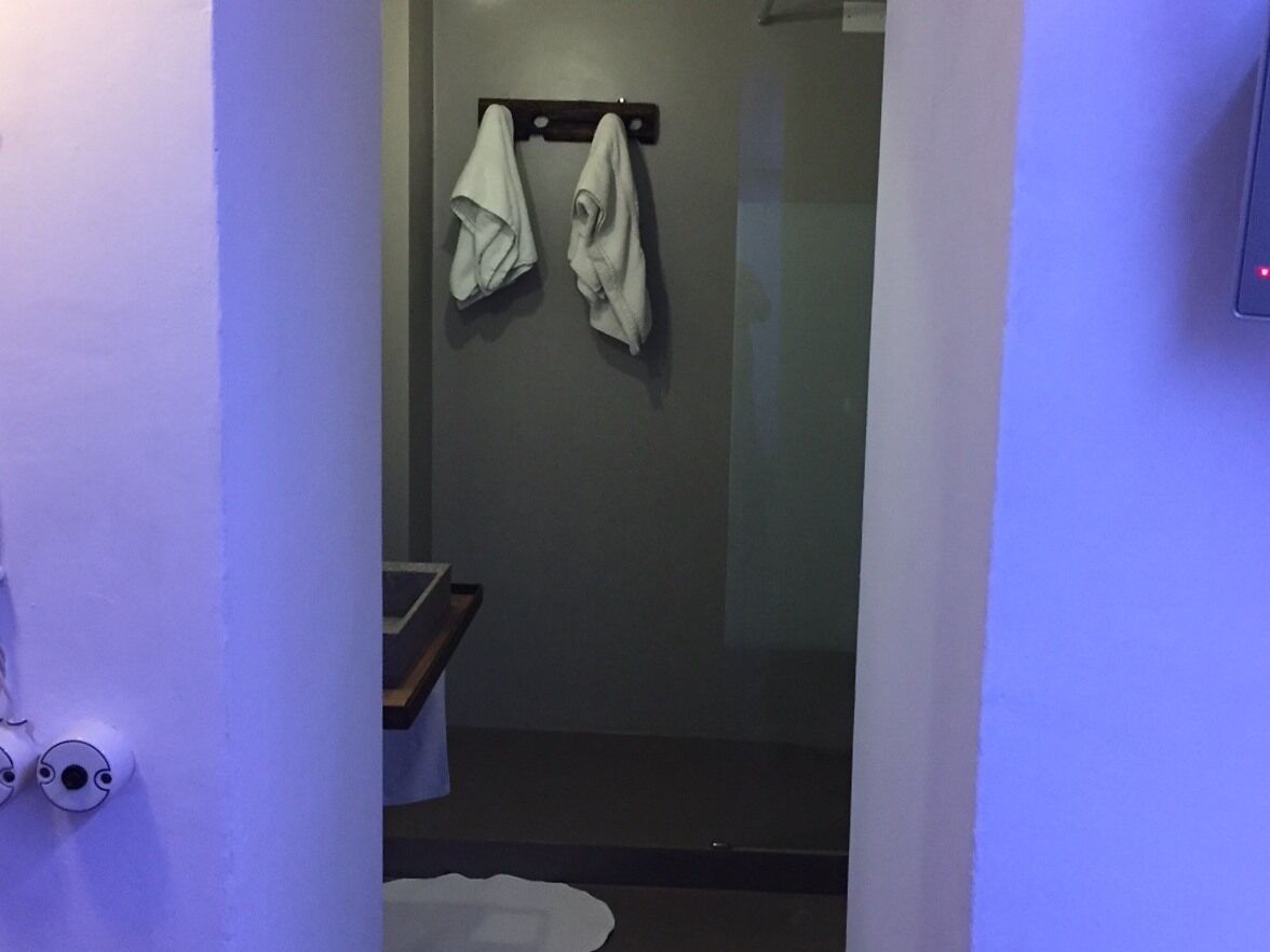 Une salle de bain avec une porte de douche en verre, un porte-serviettes avec deux serviettes et un lavabo blanc.