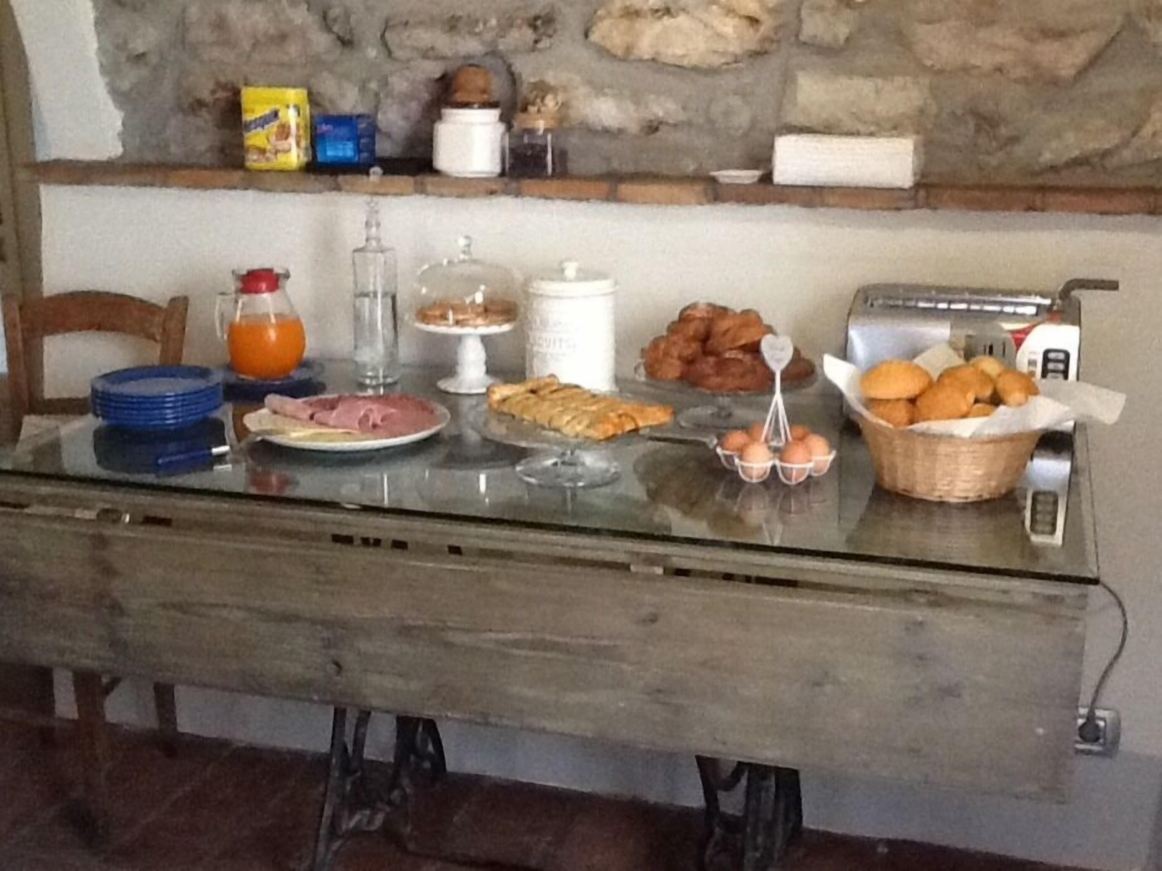 A breakfast table with plates of food, a basket of bread, a toaster, and a coffee maker.