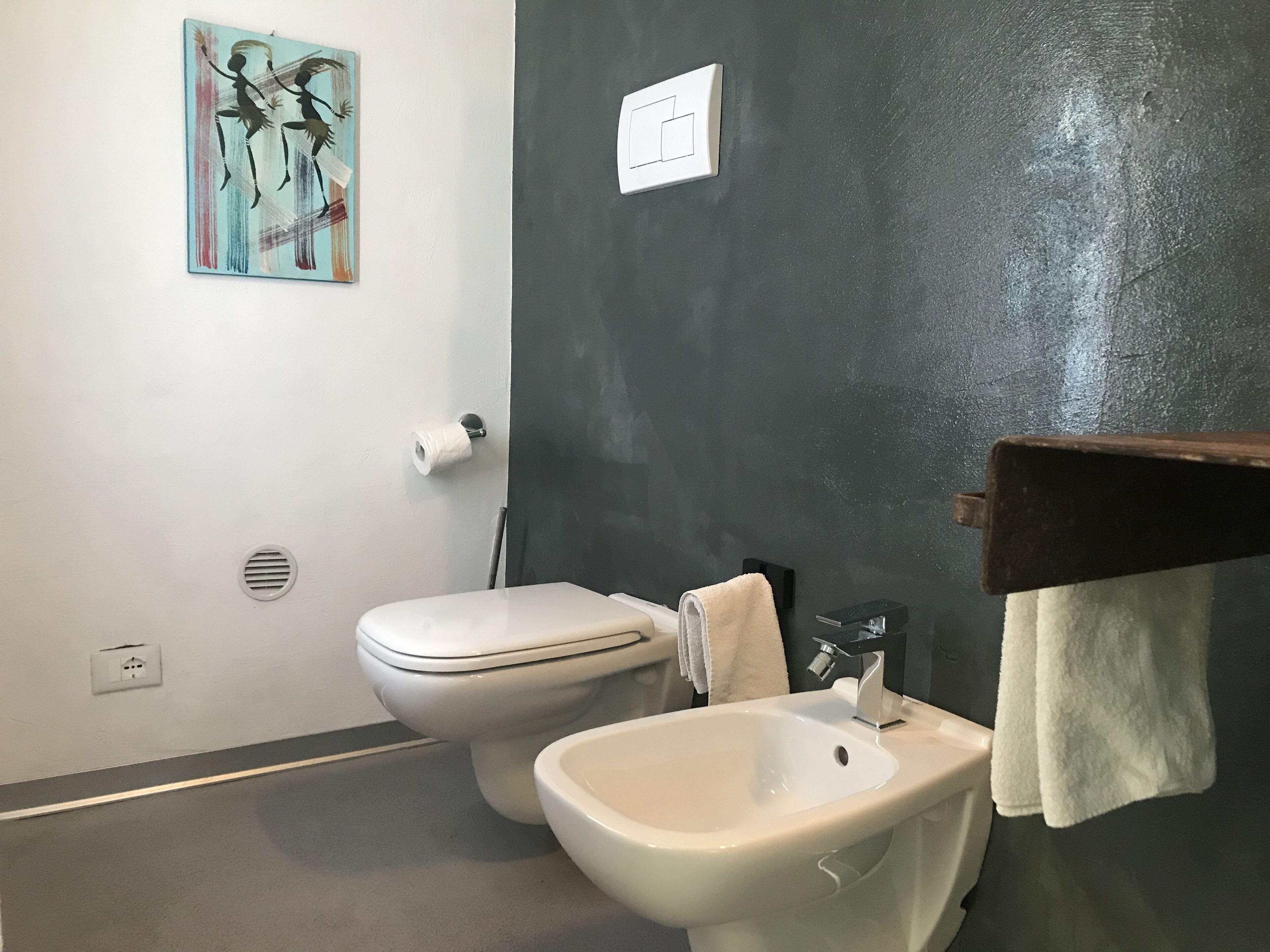 A bathroom with a toilet, bidet, and a towel rack.