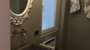 Ein Badezimmer mit großem Spiegel, Waschbecken, Fenster und Handtuchhalter.