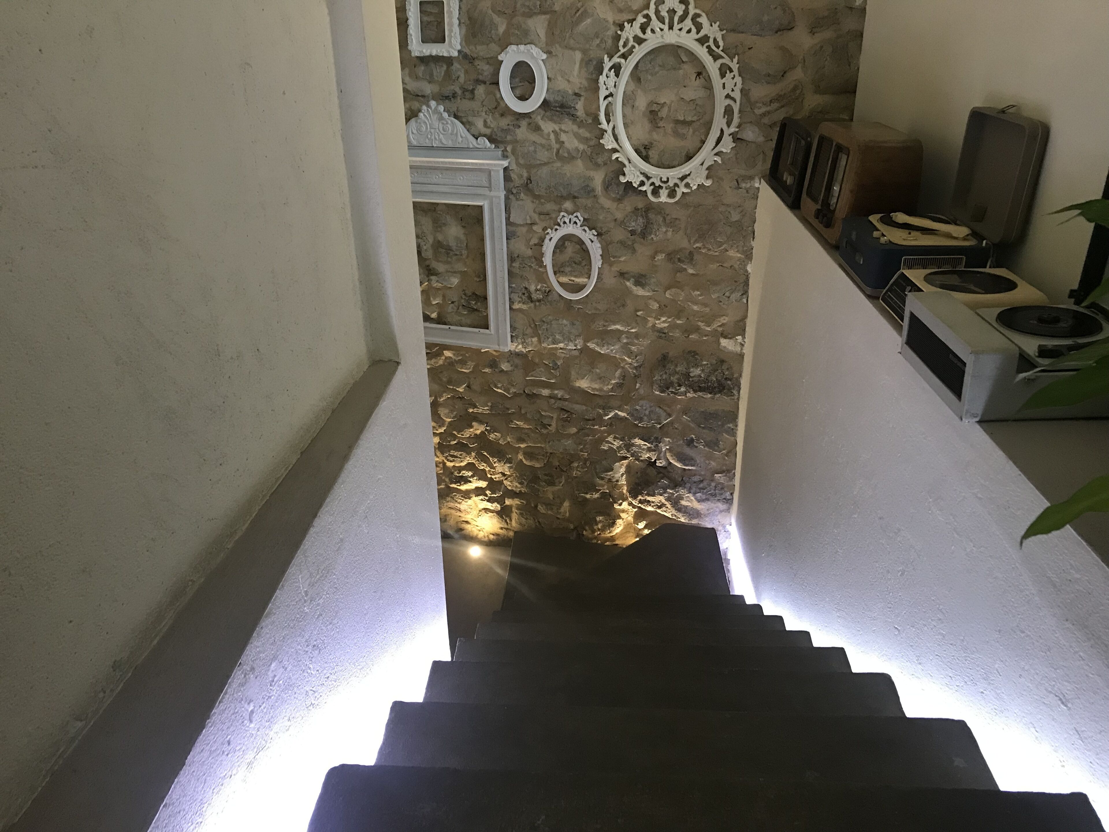 A staircase leading to a room with a stone wall and decorative mirrors.