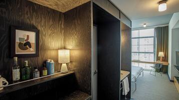 Hotelkamer met een houten wand, nachtkastje met een lamp, een bed, een stoel en een raam met gordijnen.
