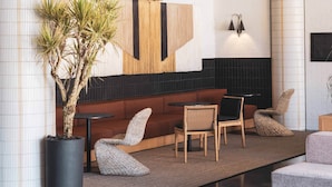 Et moderne loungeområde med sofa, stole og en stor stueplante.