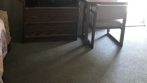 Una habitación de hotel con un mueble de madera para entretenimiento, un escritorio y un espejo en la pared.