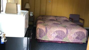 Ein Hotelzimmer mit einem Bett, einem Schreibtisch, einer Lampe und einem Deckenventilator.