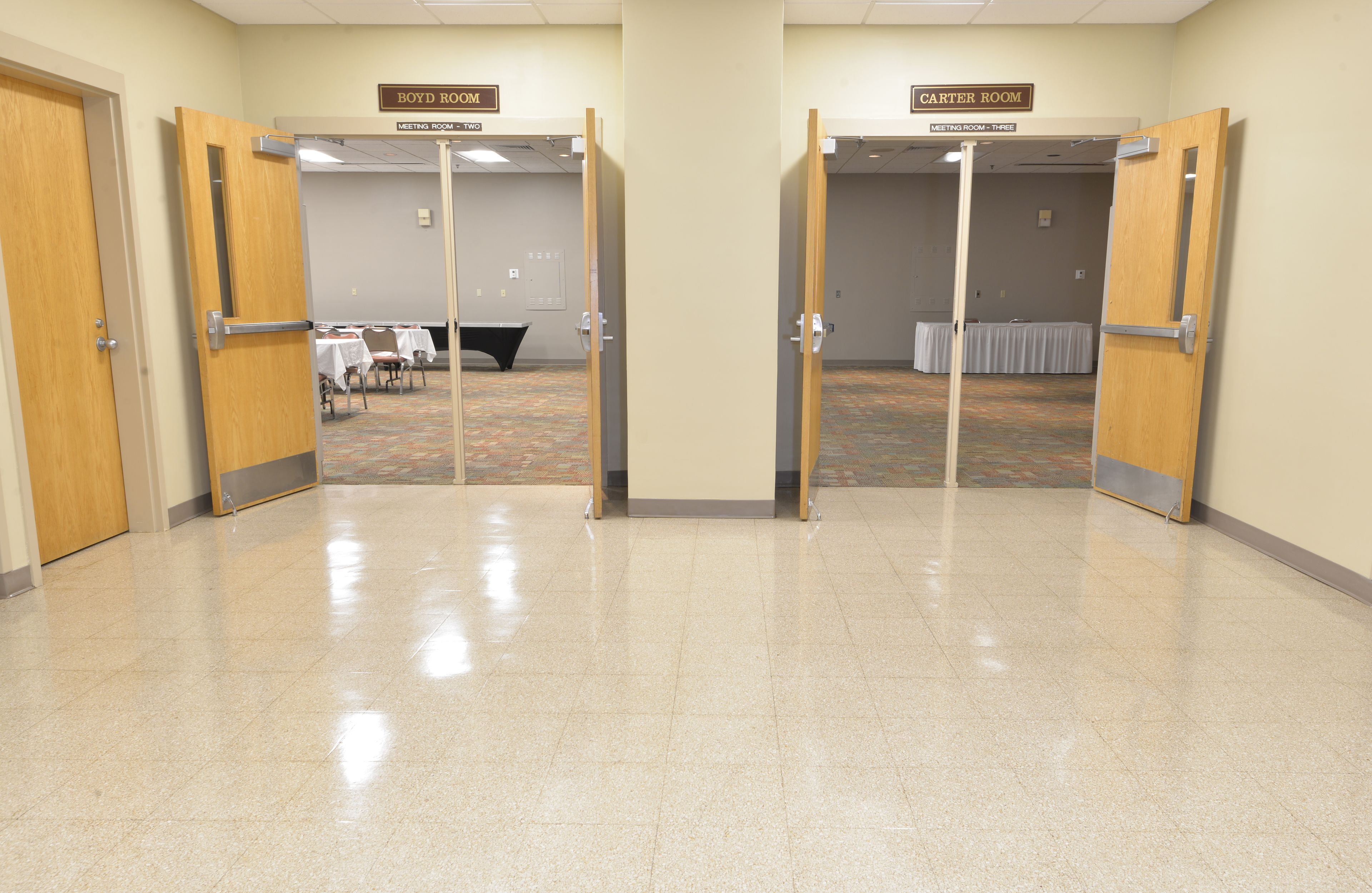 A hotel corridor with doors to Boyd Room and Carter Room, meeting rooms in the background, and a carpeted floor.