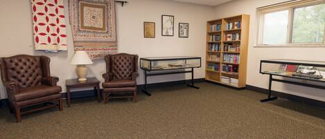 A library with leather chairs, a glass display case, and a bookshelf.
