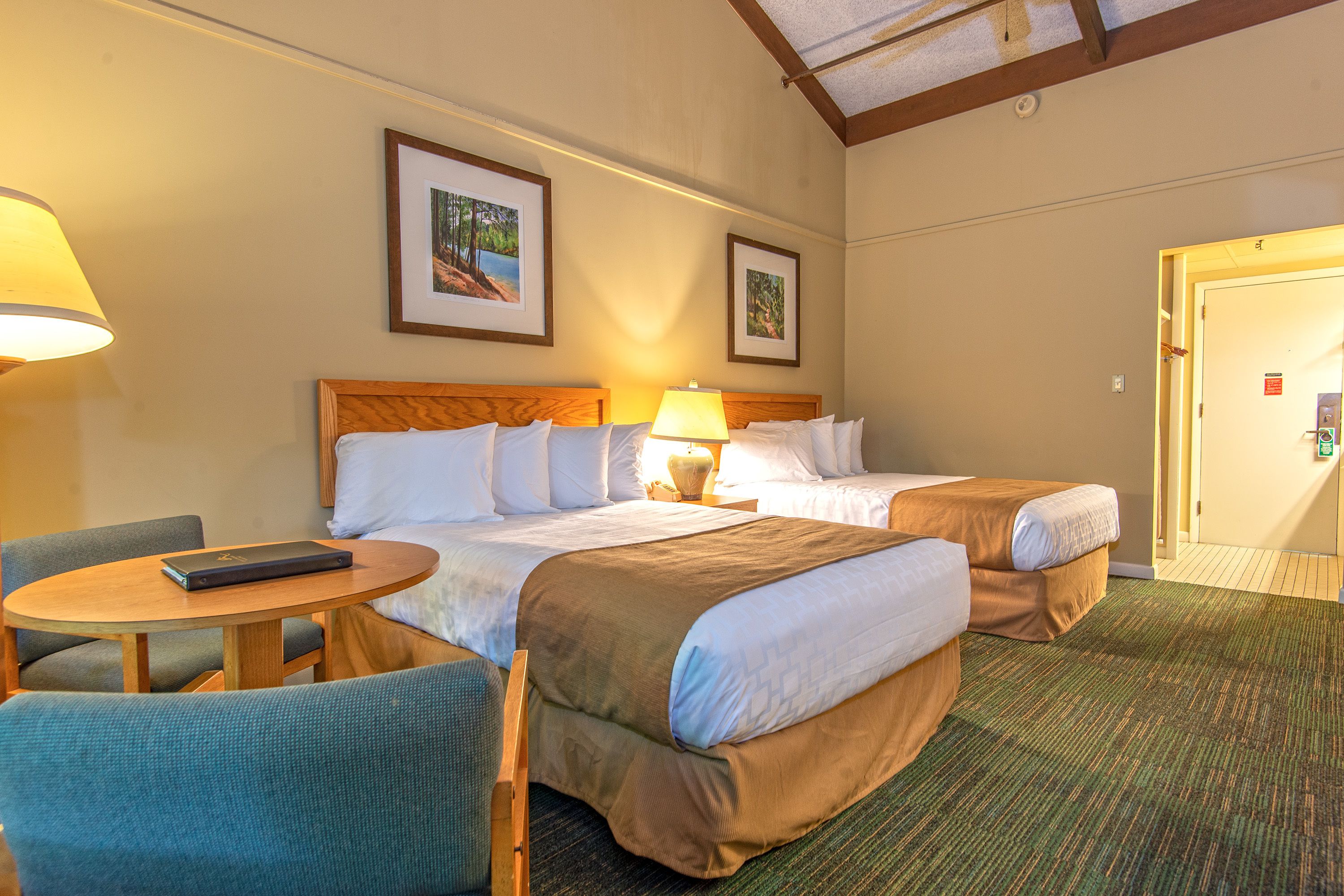 A hotel room with two beds, a desk, and a chair.