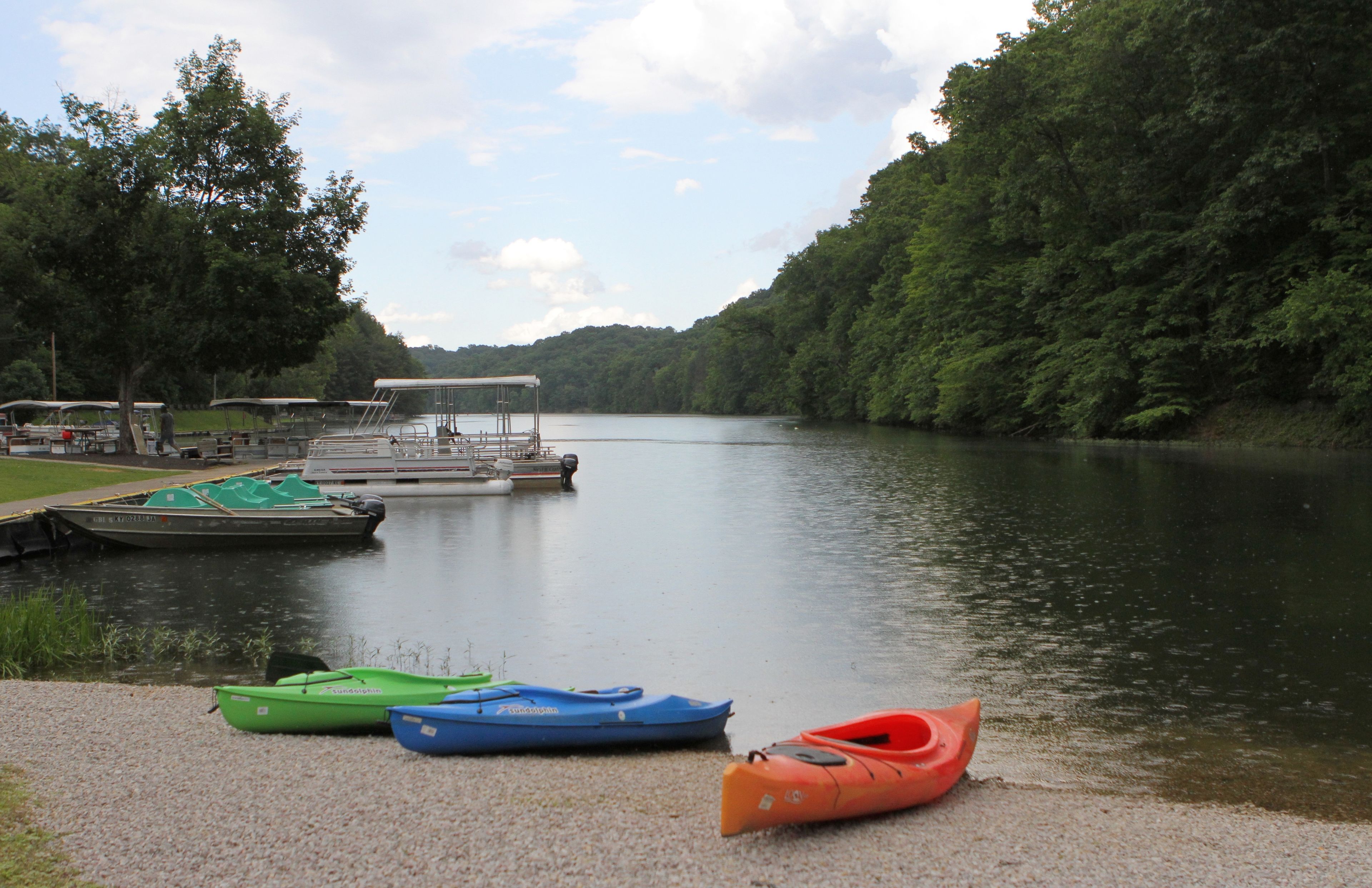 A calm lake with boats docked at a pier, surrounded by dense forest.