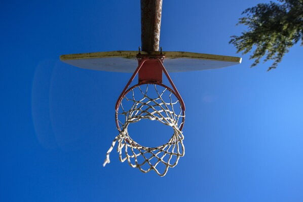Una canasta de baloncesto con red contra un cielo azul despejado.