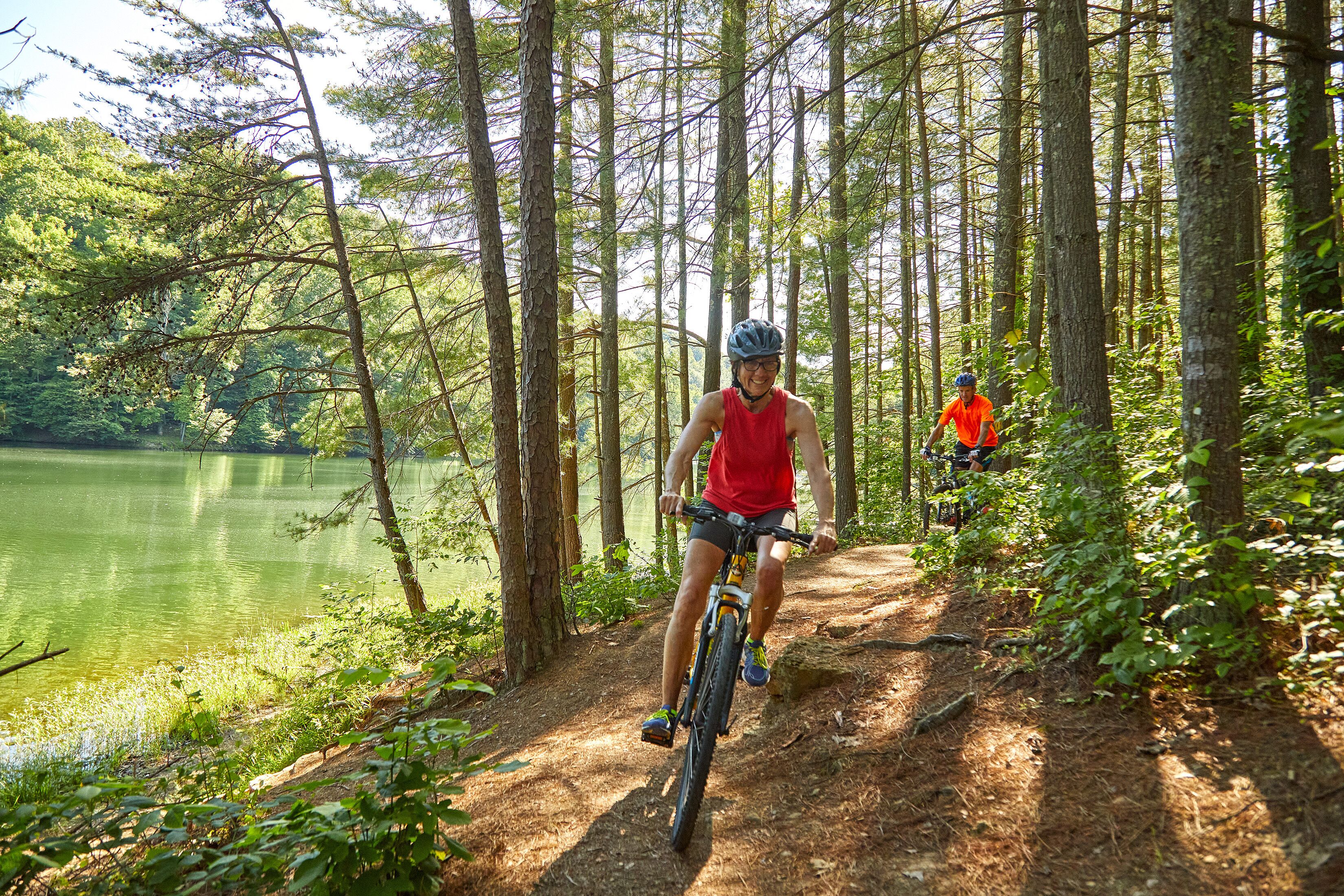 A forested trail with a lake.