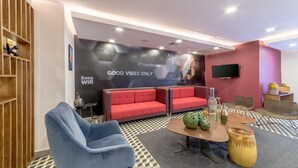 Un espace détente moderne avec un canapé rouge, un fauteuil bleu et un sol à carreaux.