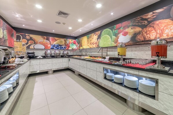 A buffet area with a variety of food items, including fruits, pastries, and beverages.