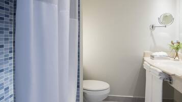 Une salle de bain moderne équipée de toilettes, d’un lavabo avec un miroir et d’un rideau de douche.