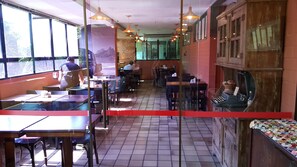 A restaurant interior with tiled floors, tables, chairs, and hanging pendant lights.