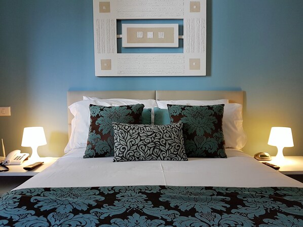 A neatly made bed with patterned pillows and a decorative wall hanging.
