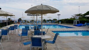 A poolside area with lounge chairs, umbrellas, and a swimming pool. - Barrabella Pé na areia (Rio de Janeiro)