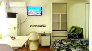A small, compact room with a bed, a desk, a chair, a television mounted on the wall, and a wardrobe. - Isla Verde (Rosario)