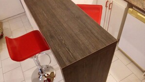 Una cocina con encimera de madera oscura, una silla roja y armarios blancos.
