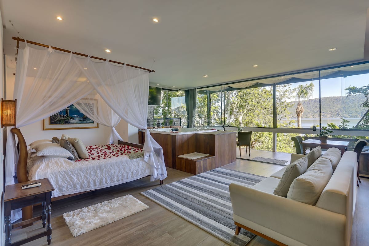 Un dormitorio con cama, mesita de noche y vistas al exterior.