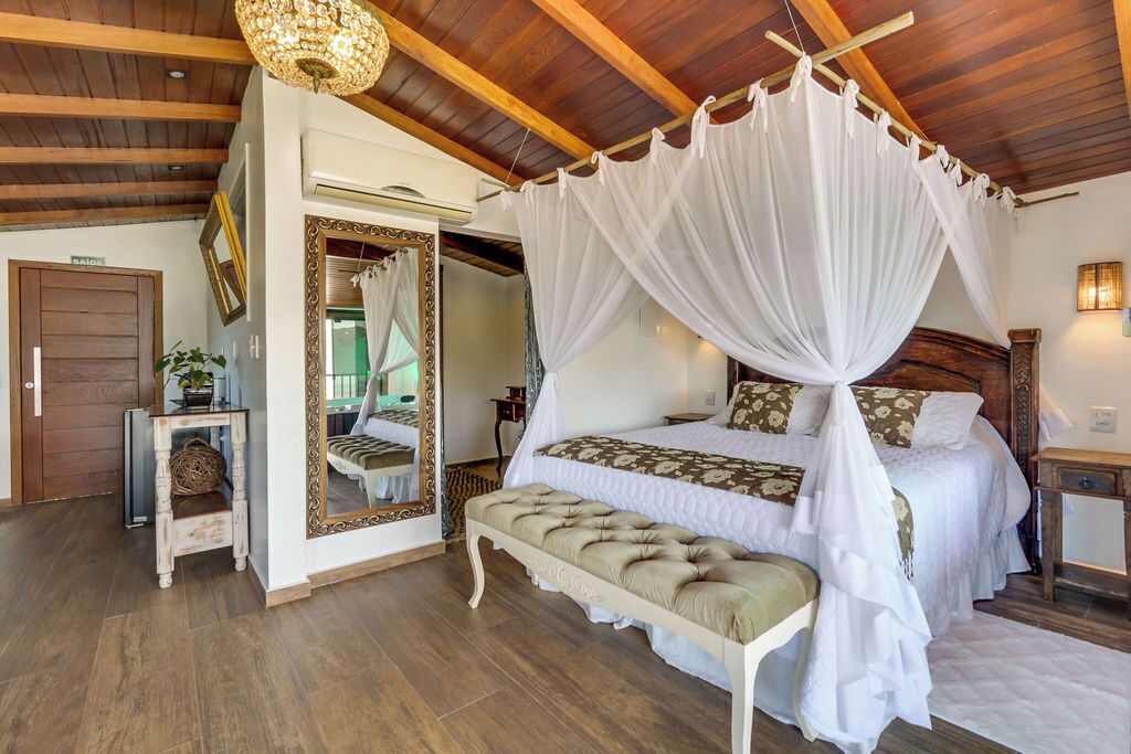 Una camera da letto con un letto a baldacchino, uno specchio, una panca e un soffitto in legno.