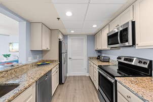 Cocina compacta con encimeras de granito, electrodomésticos de acero inoxidable y vista al área de estar.