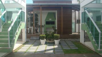 A modern outdoor area with a wooden deck, potted plants, and a green wall.