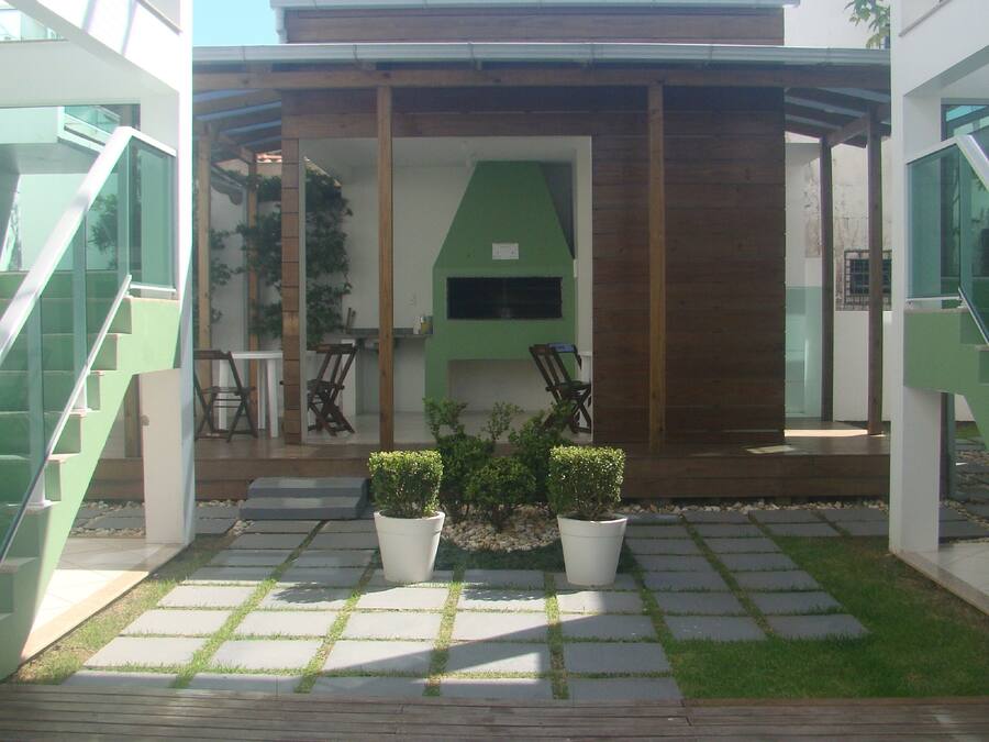 A modern outdoor area with a wooden deck, potted plants, and a green wall.