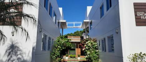 A modern building with a central atrium, white walls, and a clear blue sky.