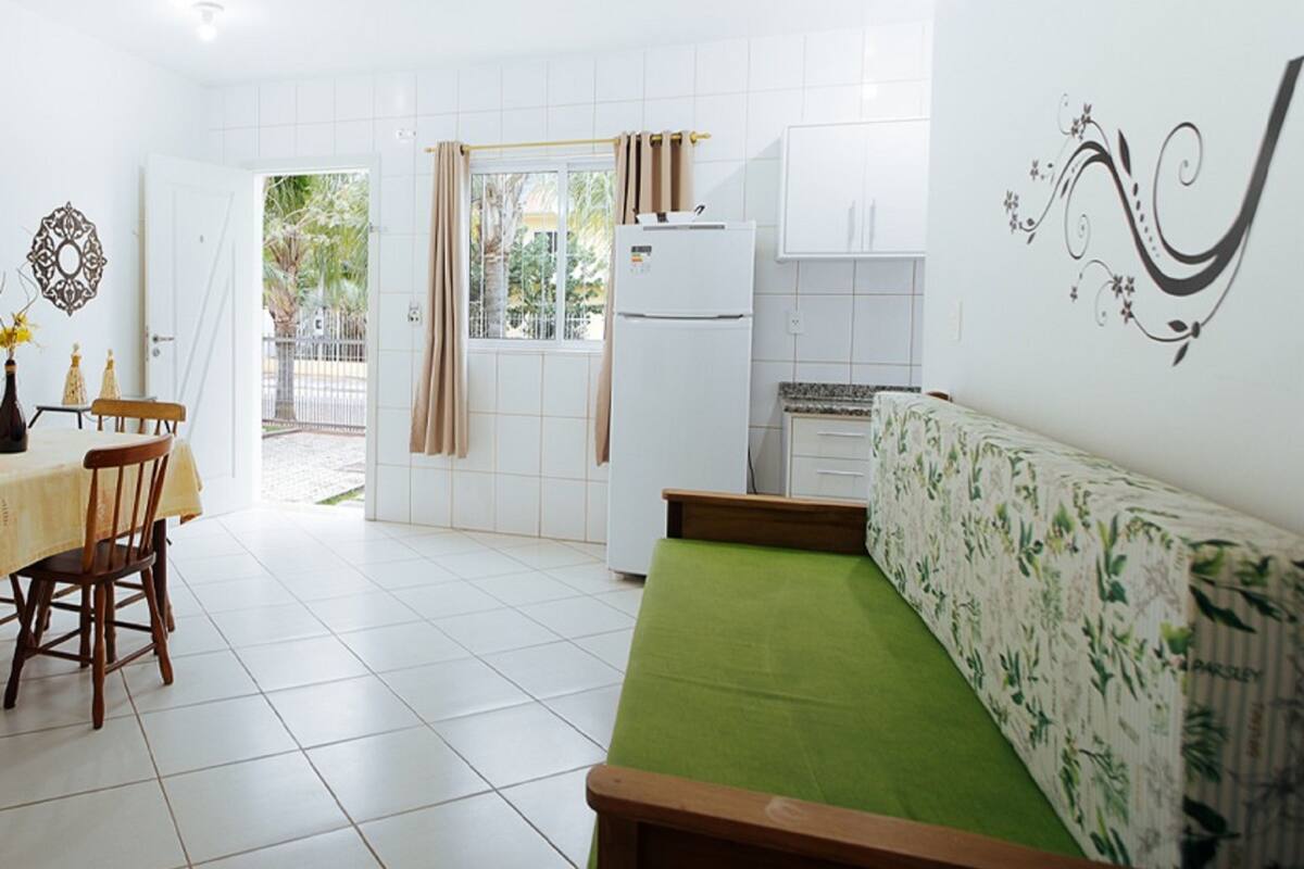 A bright, white interior with a dining area, a sofa, and a kitchen.