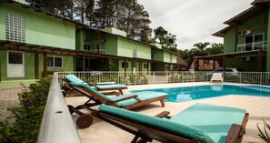 Una piscina al aire libre, sillones reclinables de piscina