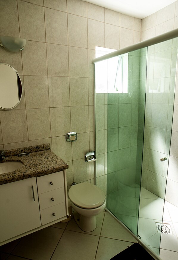 A bathroom with a toilet, sink, and glass shower enclosure.