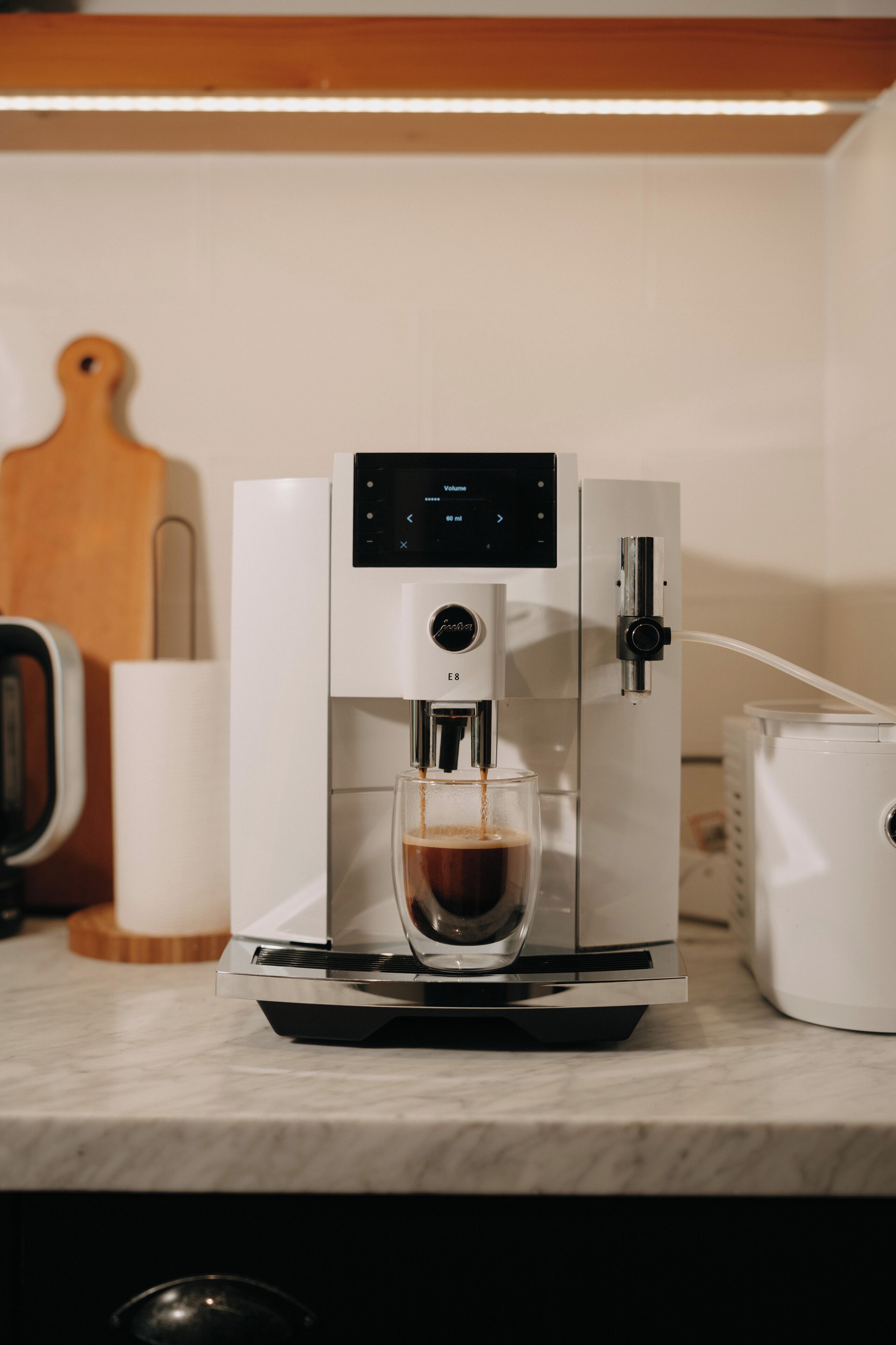 Une machine à café est posée sur un plan de travail de cuisine, et une tasse de café est en train d’être remplie.