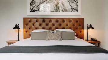 A neatly made bed with a tufted headboard, two bedside lamps, and a framed picture on the wall.
