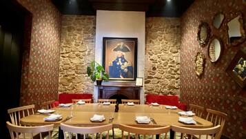 Un comedor con pared de piedra, una araña y un retrato enmarcado.