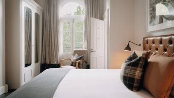 Une chambre à coucher avec un grand lit, une chaise, une armoire et une fenêtre avec des rideaux.