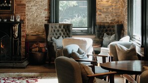 Una habitación acogedora con pared de piedra, chimenea y asientos cómodos.