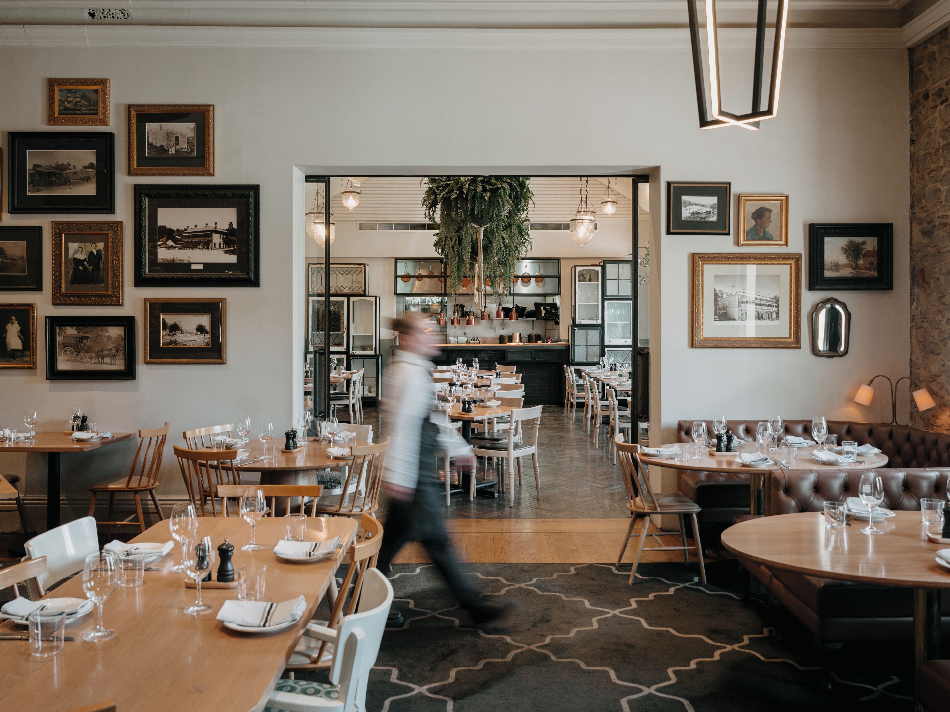 A restaurant with multiple dining tables, chairs, and framed pictures on the walls.