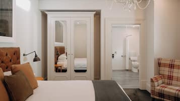 A bedroom with a bed, a wardrobe, a chair, and a bathroom visible through an open door.