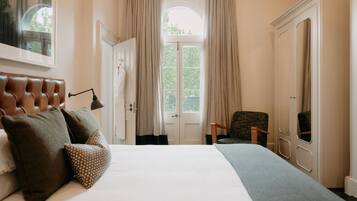 Une chambre à coucher avec un grand lit, une chaise, une armoire et une porte donnant sur un balcon.