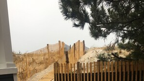 A wooden deck with a sandy path leading to a wooden fence.
