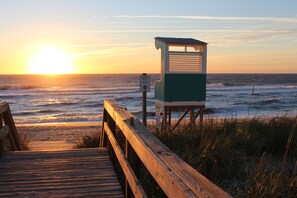 A wooden boardwalk leading to a lifeguard tower at a beach. - Ocean View From Both Of Our Decks....at 1218 S Lake Park #2 (Carolina Beach)