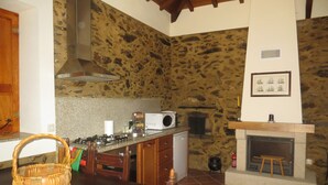 Una cocina con pared de piedra, chimenea y microondas.