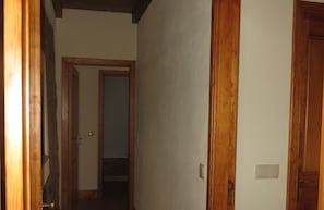 A narrow hallway with wooden doors and a visible light switch on the wall.