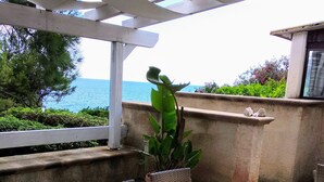An outdoor patio with a glass table and wicker chairs, overlooking a body of water. - Castro: House with private access to the sea (Castro)