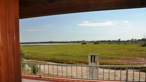 A view from a balcony with a railing, overlooking a large grassy field and a distant tree line. - Villa Lido di Spina "Adriatic coast" (Lido di Spina)