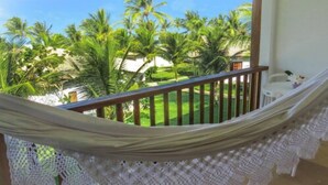 A hammock on a balcony with a view of a lawn and palm trees. - Acquapipa Resort (Tibau do Sul)