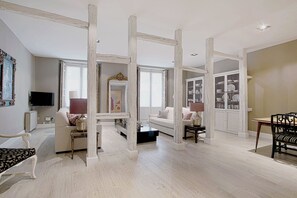 A spacious living room with a high ceiling, a television mounted on the wall, and a dining area with a table and chairs. - Genteel Home Huertas (Madrid)