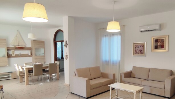 A modern living room with a dining area, two sofas, a coffee table, and pendant lights. - Residenza I Filari: a villa surrounded by greenery. (Alghero)