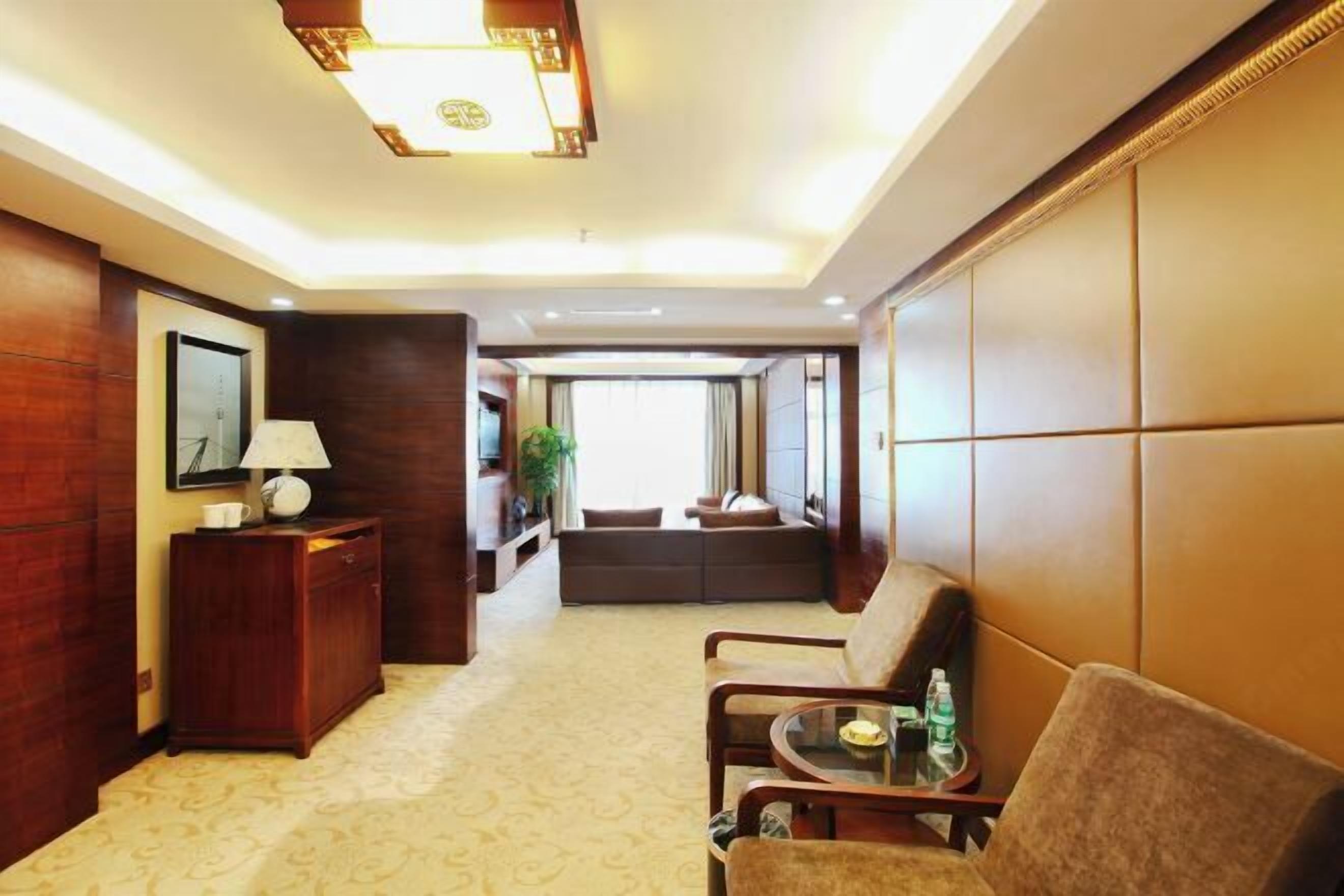A hotel lobby with a reception desk, seating area, and a large window providing a view of the outside.